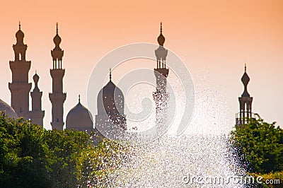 Mosques silhouettes against the yellow sky and sparkling fountain in Cairo Stock Photo