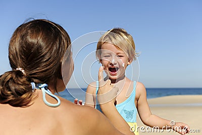 Mother applying sunscream to her happy child Stock Photo