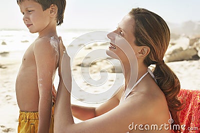 Mother Applying Sunscreen Cream On Son's Back Stock Photo