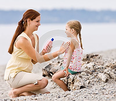 Mother applying sunscreen to daughter at beach Stock Photo