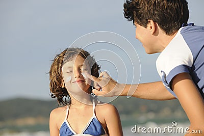 Mother applying sunscreen to daughter at beach. Stock Photo