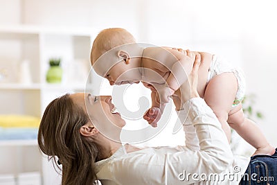 Mother and baby boy in diaper playing in sunny room. Parent and little kid relaxing at home. Family having fun together. Stock Photo