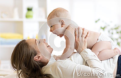 Mother and baby boy in diaper playing in sunny room. Parent and little kid relaxing at home. Family having fun together. Stock Photo