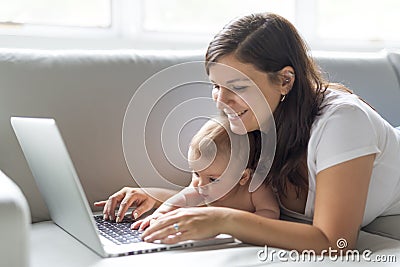 Mother and baby child are looking to play and read computer on the couch at home Stock Photo