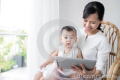 Mother and baby are looking to play and read tablet computer at Stock Photo