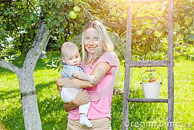 Mother with baby picking apples from an apple tree Stock Photo