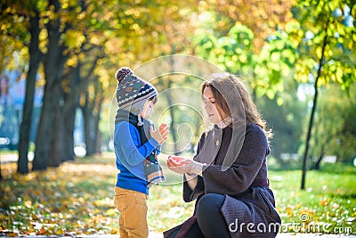 Mother and baby play in autumn park. Parent and child walk in the forest on a sunny fall day. Children playing outdoors with Stock Photo
