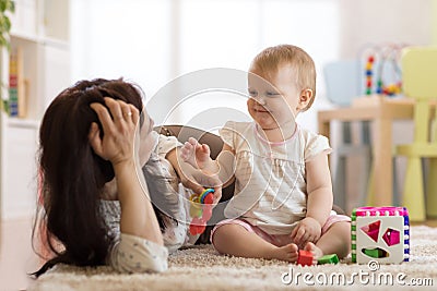 Mother and baby play with toys in nursery Stock Photo