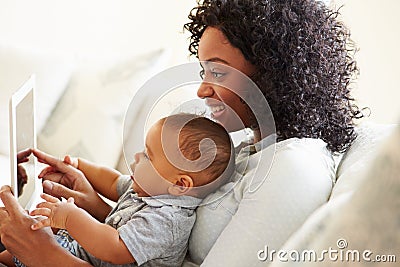 Mother And Baby Playing With Digital Tablet At Home Stock Photo