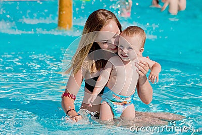 Mother and baby in swimming pool. Parent and child swim in a tropical resort. Summer outdoor activity for family with kids. Stock Photo