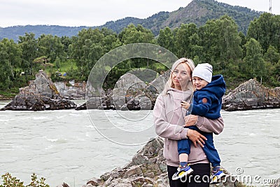 Mother and baby walking on nature outdoors. Family in rocky nature background with river. Loving woman with child in countryside. Stock Photo