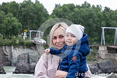 Mother and baby walking on nature outdoors. Family in rocky nature background with river. Loving woman with child in countryside. Stock Photo
