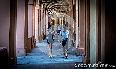 Mother in black hat and daughter in shorts walking down promanade in sneakers and shorts and pants Stock Photo