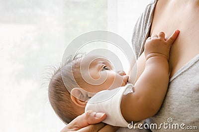 Mother breastfeeding her newborn baby beside window Stock Photo