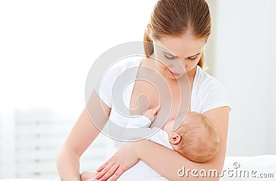 Mother breastfeeding newborn baby in white bed Stock Photo