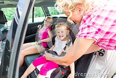 Mother buckling up on child in car Stock Photo