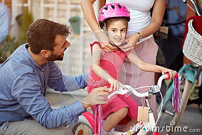 Mother buying at happy girl bicycle helmet in bike shop Stock Photo