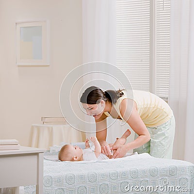 Mother changing babyï¿½s diaper on bed Stock Photo