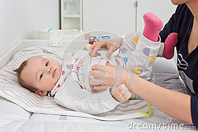 Mother changing diapers of a nine months old baby girl daughter Stock Photo