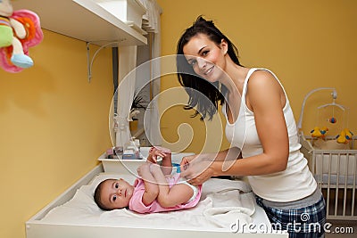 A mother changing her baby daughter nappy . Stock Photo