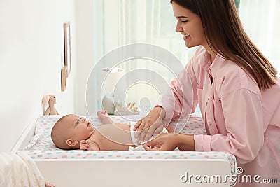 Mother changing baby`s diaper on table at home Stock Photo