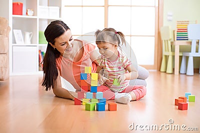 Mother and child building from toy blocks at home. Family concept. Stock Photo