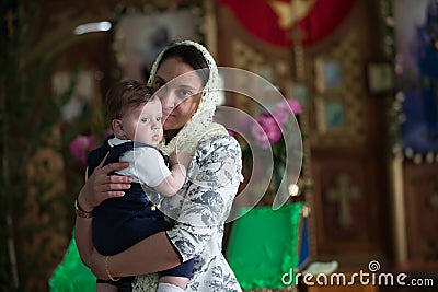 Mother with child in church. An infant in the arms of the godmother in the temple Editorial Stock Photo