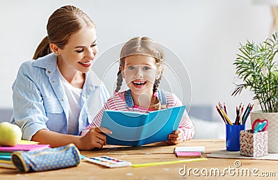 Mother and child daughter doing homework writing and reading at Stock Photo