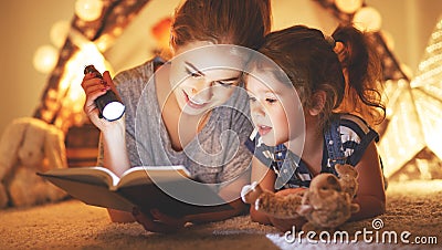 Mother and child daughter reading a book and a flashlight before Stock Photo