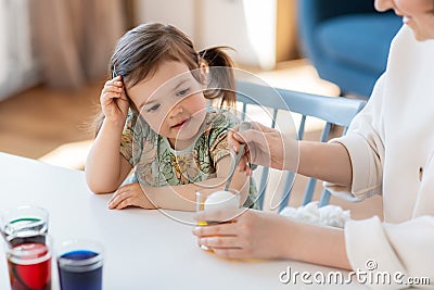 mother with child dyeing easter eggs at home Stock Photo