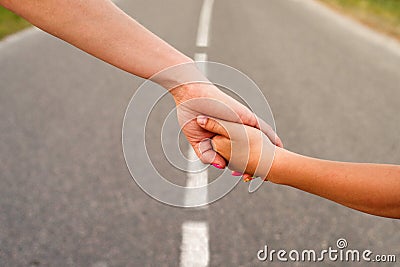 Mother and child hold hands together while walking along the highway in summer outdoors Stock Photo