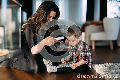 Mother and child at home - mother taking his temperature with digital thermometer Stock Photo