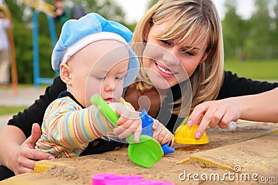 Mother and child play in sandbox Stock Photo