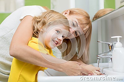 Mother and child son washing their hands in the bathroom. Care and concern for kids. Stock Photo