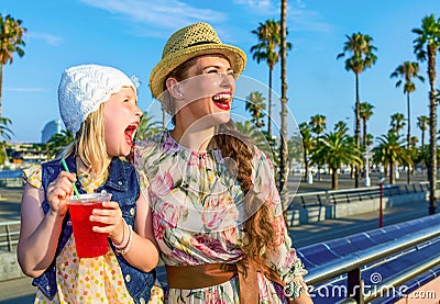 Mother and child tourists with bright red beverage looking into Stock Photo