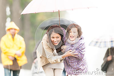 Mother and child under umbrella in rainy weather. Stock Photo