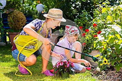 Mother and child watering flowers in garden Stock Photo