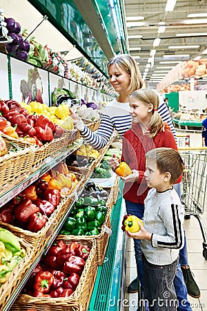 Mother and children with bell pepper in supermarket Stock Photo