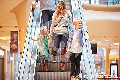 Mother And Children On Escalator In Shopping Mall Stock Photo