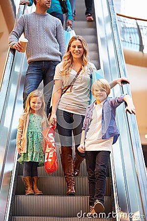 Mother And Children On Escalator In Shopping Mall Stock Photo