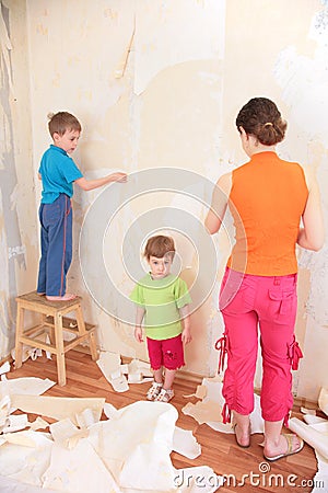 Mother with children remove old wallpapers from wa Stock Photo