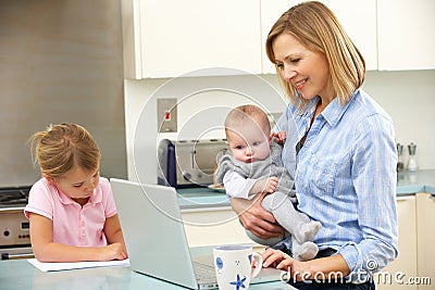 Mother with children using laptop in kitchen Stock Photo