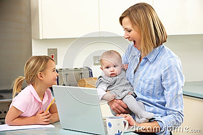 Mother with children using laptop in kitchen Stock Photo