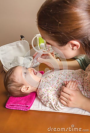 Mother cleaning mucus of baby with nasal aspirator Stock Photo