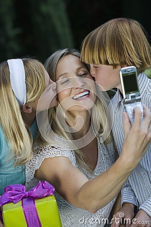 Mother Clicking Self Photo While Kids Kissing Stock Photo