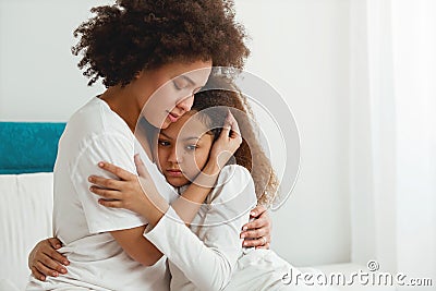 Mother comforting her daughter, sitting in the bedroom Stock Photo