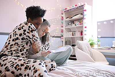 Mother Comforting Teenage Daughter In Bedroom Looking At Letter With Disappointing Exam Results Stock Photo