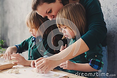 Mother cooking with kids in kitchen. Toddler siblings baking together and playing with pastry at home Stock Photo