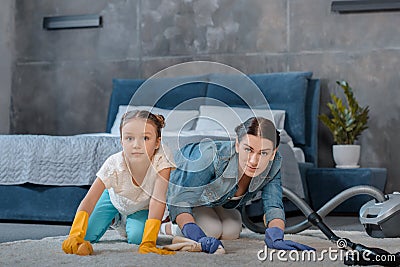 Mother and cute little daughter cleaning carpet Stock Photo