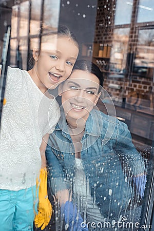 Mother and cute little daughter cleaning window together Stock Photo